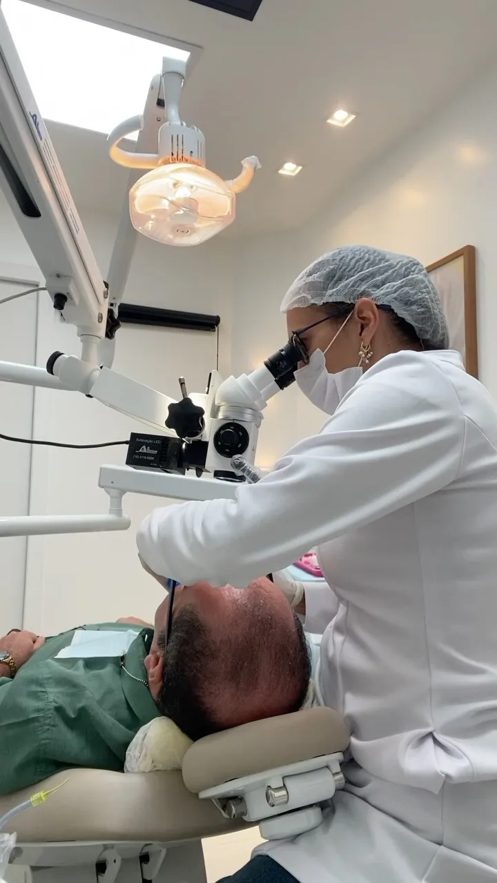 Dentista trabalhando com microscópio odontológico